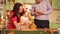 a little girl in a chef's cap with mom and dad decorates a gingerbread house