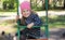 Little girl child in autumn clothes and a pink hat in the park swinging on a swing and laughing.