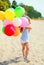 Little girl child with colorful balloons on beach