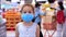 Little girl child in a mask from viruses of the epidemic of the coronavirus or viruses looks at the camera among people