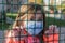 Little girl child in medical mask behind an iron fence