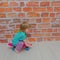 little girl, child riding a skateboard on a brick wall background