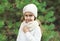 Little girl child wearing knitted hat and sweater with scarf near christmas tree