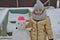 Little girl child in winter sculpts a snowman from the snow.