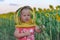 A little girl in a children`s mask of a beekeeper picks off the heads of a sunflower