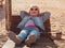 Little girl chilling resting in beach chair Happy child smiling relaxing enjoying life sun fresh air Distance e-learning