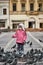 Little girl in a city square feeding pigeons