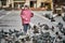 Little girl in a city square feeding pigeons