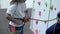 Little girl climber ties a safety knot before climbing the training wall.
