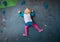 Little girl climbing on artificial boulders wall in gym