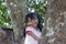 Little girl climbing on  the big tree and sitting cute smile in the countryside.