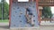 Little girl is climbing on climbing wall in the public playground