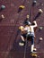 Little girl climbing a  vertical rock  wall  with helmet on her head safely tied with rope for protection