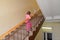 The little girl climbs up on a ladder handrail the second floor