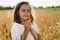 Little Girl closed her eyes, praying in a field wheat. Hands folded in prayer.