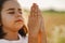 Little Girl closed her eyes, praying in a field wheat. Hands folded in prayer.