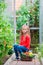 Little girl collecting crop cucumbers and tomatos in greenhouse. Portrait of kid with big busket full of vegetables in