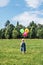 A little girl with colorful balls standing with his back and looks towards the forest. On the balloon inscription happy birthday