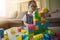 Little girl in a colorful shirt playing with construction toy blocks building a tower