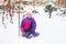 Little girl in colorful suit play in snow in back yard in cold