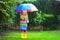 Little girl with colorful umbrella playing in the rain.