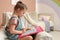 Little girl coloring antistress page in armchair