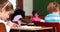 Little girl colouring in the classroom and smiling at camera