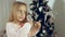 Little girl combing her hair standing near the Christmas tree