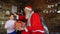 Little girl comes to Santa Claus, presents New Year gift and hugs Christmas grandfather