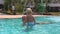 Little girl comes up to mother in pool and pulls hand