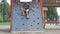 Little girl is coming down on climbing wall in the public playground