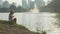 Little girl in country style hat feeding fishes in a park lake in slow motion