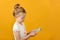 Little girl counts money in hands while thinking about shopping, on yellow background