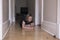 Little girl crouched on corridor hardwood floor playing with small and large glass marbles in soft focus
