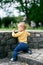 Little girl crouched on stone steps near the fence in the park