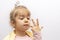 A little girl in a crown demonstrates toy rings on her fingers, children`s jewelry and bijouterie.