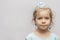 A little girl in a crown and earrings demonstrates toy rings on her fingers, children`s jewelry and costume jewelry.