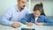 Little girl crying while doing homework together with strict father