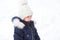 Little girl crying outside in winter. A child in warm clothes is upset, cold, wipes away tears, screams, is capricious and