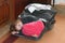 A little girl curled up in the lid of a suitcase filled with things