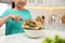 Little girl with cutting board and knife scraping  vegetable peels into bowl on kitchen table, closeup