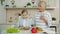 Little girl cutting vegetables making salad while granny with smartphone talking teaching kid