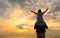 little girl on dad`s shoulders on the background of the setting sun on a seaside beach