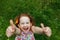 Little girl with daisy in her hairs, showing thumbs up.