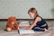 little girl in dark blue dress reading book sitting on the floor near teddy bear. Child reads story for toy.