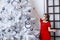 Little girl decorates the Christmas tree in red dress