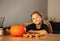 A little girl decorates a pumpkin in a room for Halloween. Kids decorate home. Children carve pumpkin. Spooky Halloween fun