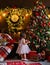 A little girl is decorating a Christmas tree with toys. Cute baby is getting ready to go home to celebrate Christmas