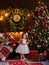 A little girl is decorating a Christmas tree with toys. Cute baby is getting ready to go home to celebrate Christmas