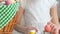 Little girl decorating egg with paint, Easter greeting basket standing on table